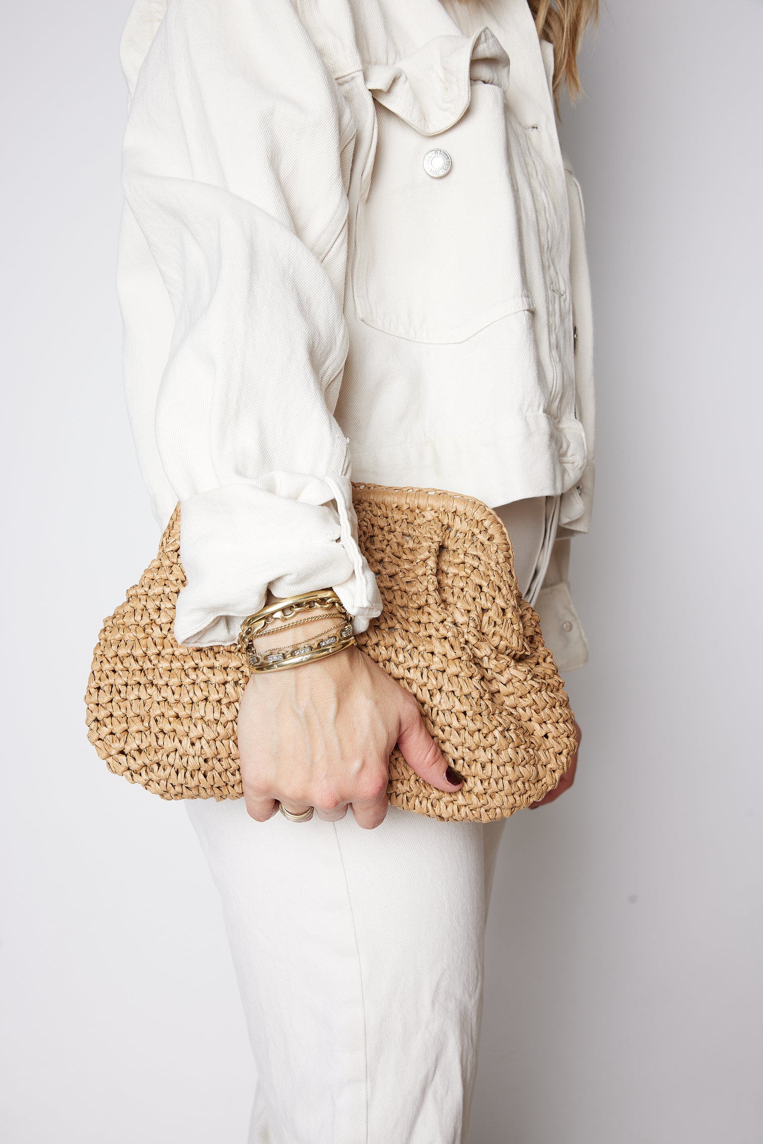 model wearing cream jeans and holding brown straw slouchy bag