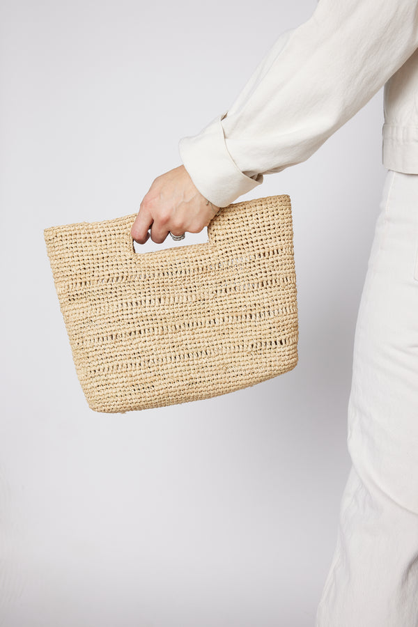 Model holding tan straw bag