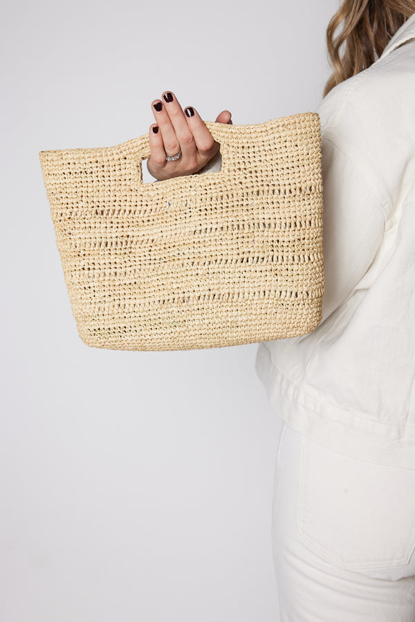 Model holding tan straw handheld bag