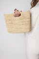 Model holding tan straw handheld bag