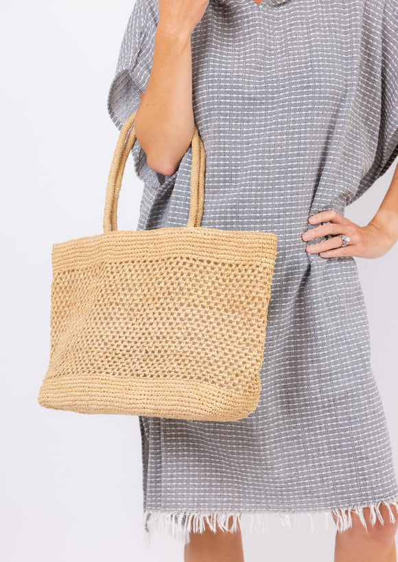 Model holding raffia straw tote