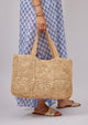 Model holding a straw tote and wearing a blue kaftan