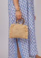 Model holding straw bag with round tortoise handles