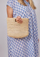 Model holding tan straw bag and wearing blue kaftan