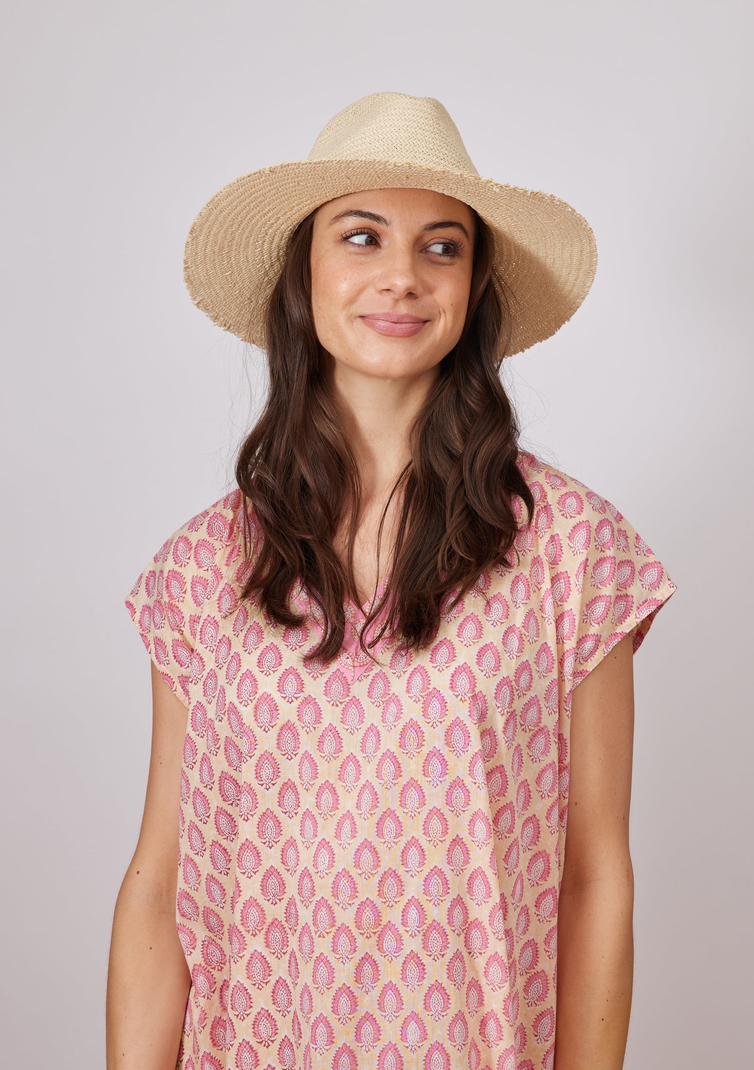Model looking to her left wearing fringed straw hat