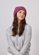 Model smiling and wearing raspberry colored cuff beanie