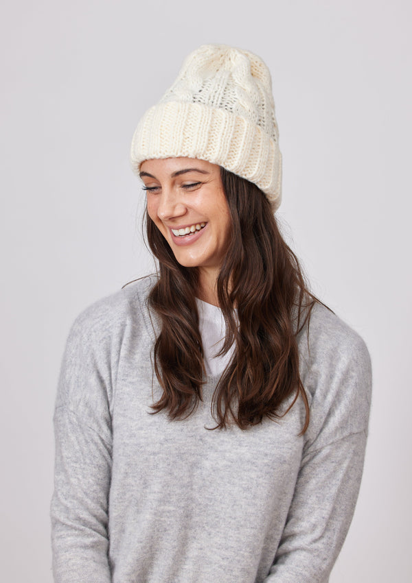 Ivory cable knit cuffed beanie on model wearing grey sweater
