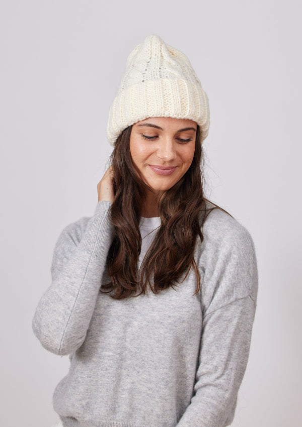 Model wearing ivory cuffed beanie and playing with hair