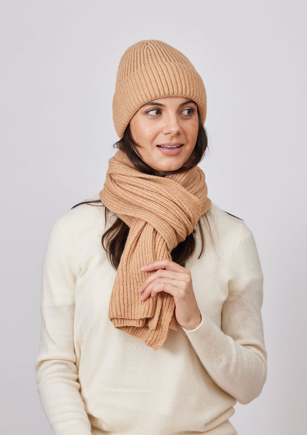 Model wearing a camel brown ribbed knit beanie and scarf and looking to her left