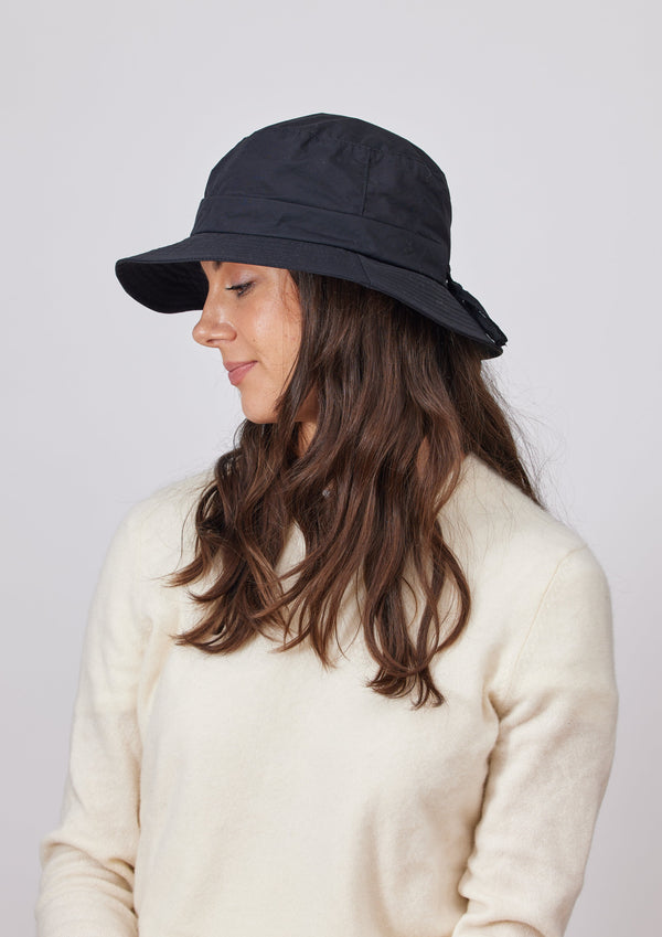 Model wearing ivory sweater and black water resistant bucket hat