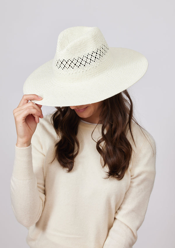 Model wearing white perforated sun hat and holding brim