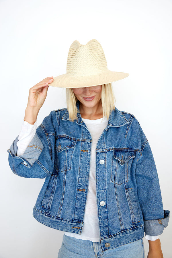 Model holding brim of tan perforated and vented sun hat