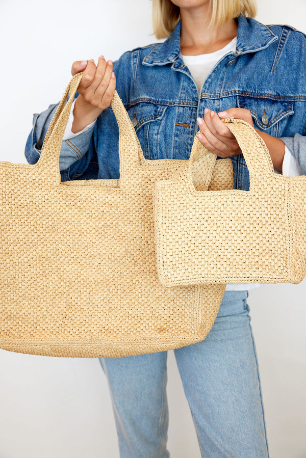 Model holding large and small woven straw bags