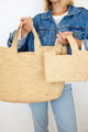 Model holding large and small woven straw bags