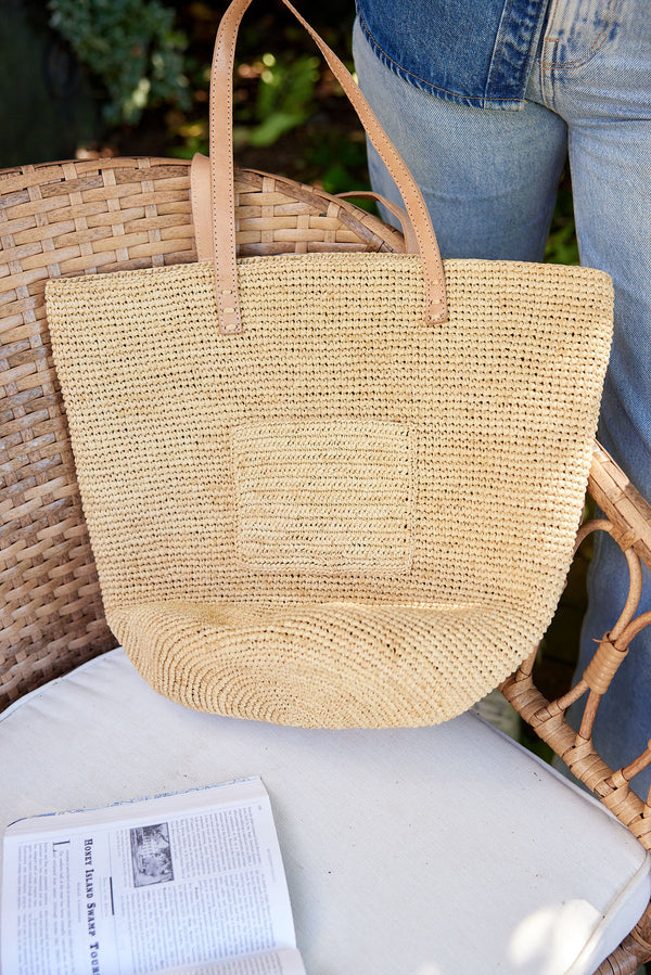 Straw tote sitting in chair with a book