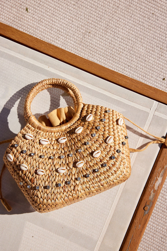 small straw bag with shell and rhinestone detail on beach chair