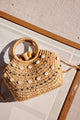 small straw bag with shell and rhinestone detail on beach chair