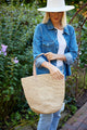 Model taking a straw bag off of her shoulder