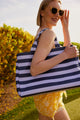 Close up of model holding blue and lavender striped beach bag