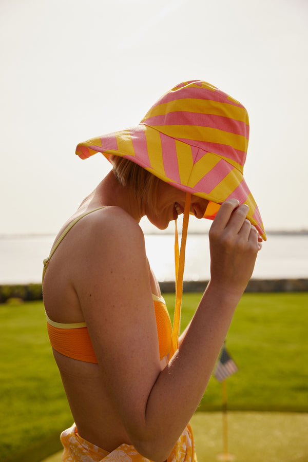 Model looking down while wearing a striped sunhat