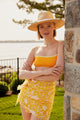Model wearing yellow floral sarong and straw sunhat