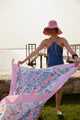 Model wearing pink hat and printed beach blanket