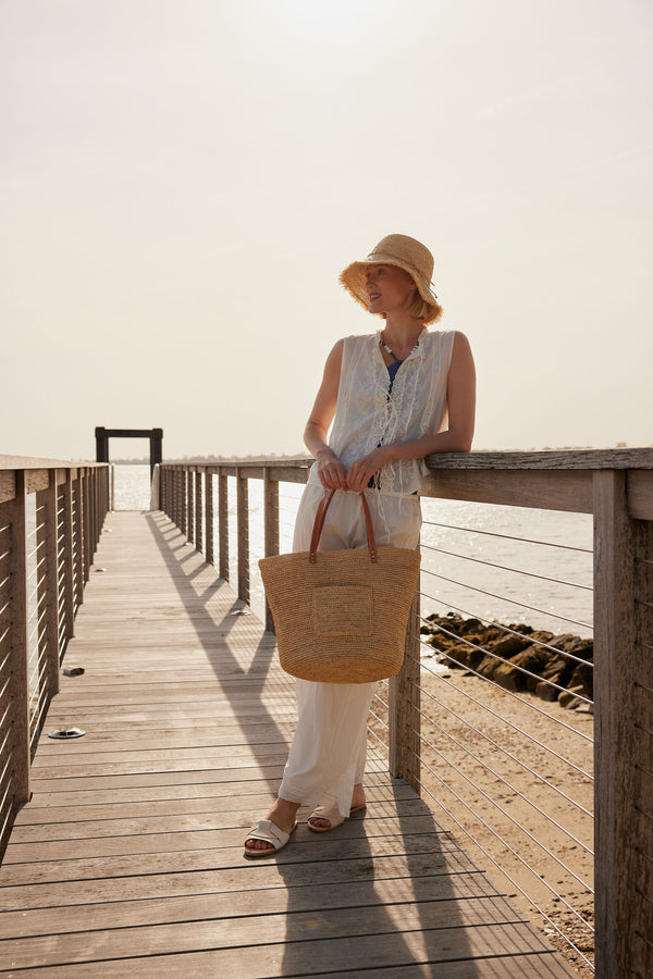 Model holding a straw tote and wearing a bucket hat