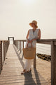 Model holding a straw tote and wearing a bucket hat