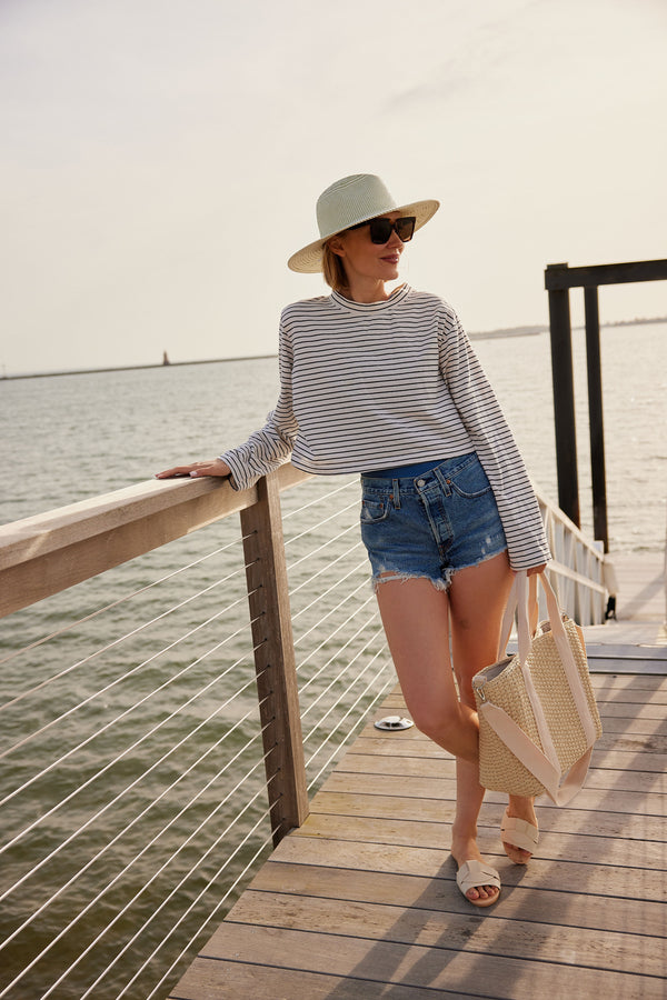 Model wearing a sunhat and holding a straw cooler tote