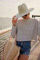 Model holding brim of green and white sunhat and straw cooler tote