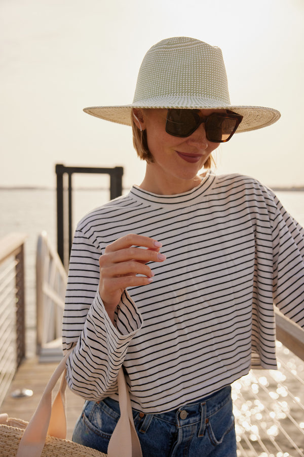 Model wearing green and white sunhat and straw cooler tote