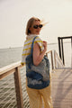 Model holding blue straw fisherman bag