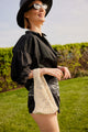 Model holding light tan cotton mini bag and black outfit