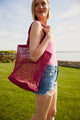 Model holding pink straw fisherman bag