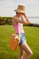 Model wearing coral and yellow striped cooler bag over her shoulder