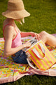 Model sitting and looking into coral and yellow striped cooler bag