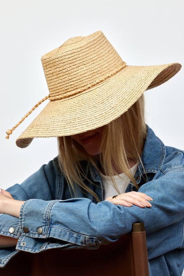 Model looking down and wearing brimmed straw sun hat with straw trim