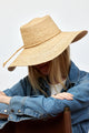 Model looking down and wearing brimmed straw sun hat with straw trim