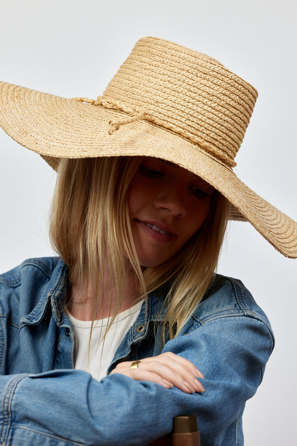 Close up of model wearing brimmed straw sun hat with straw trim