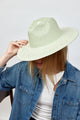 Model holding brim of mint and natural colored sun hat