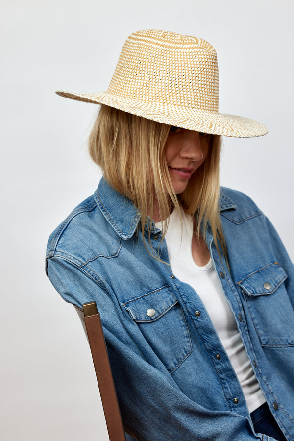 Model wearing tan and white woven sun hat and denim shirt