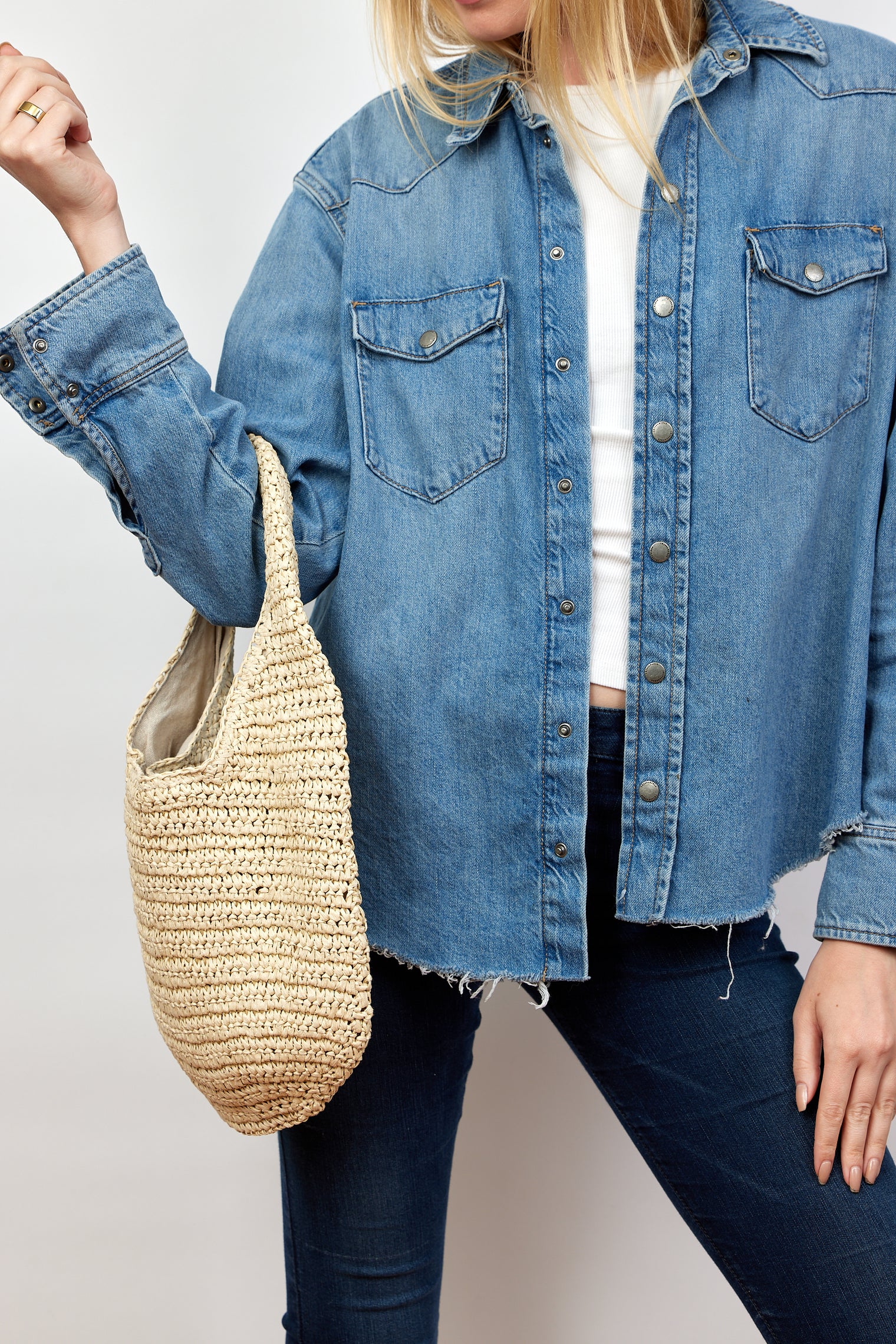 Model holding paper straw slouchy bag and wearing a denim shirt