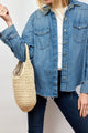 Model holding paper straw slouchy bag and wearing a denim shirt