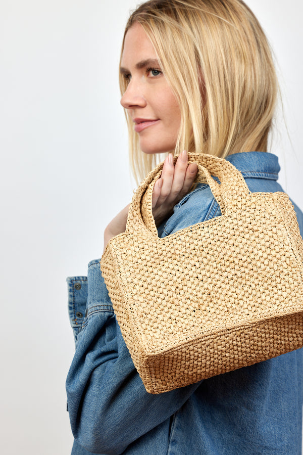 Model holding small structured woven straw bag