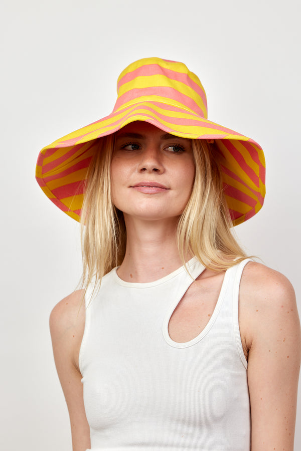 Model wearing coral and yellow striped bucket hat and white tank
