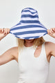Model wearing blue and lavender bucket hat and holding brim