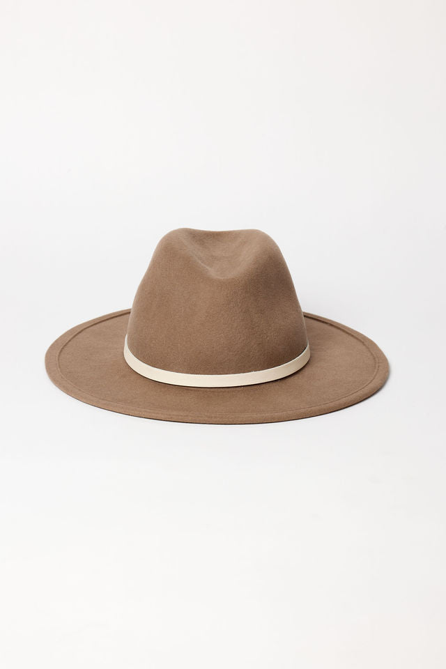 Brown fedora hat with a white band on a light beige background