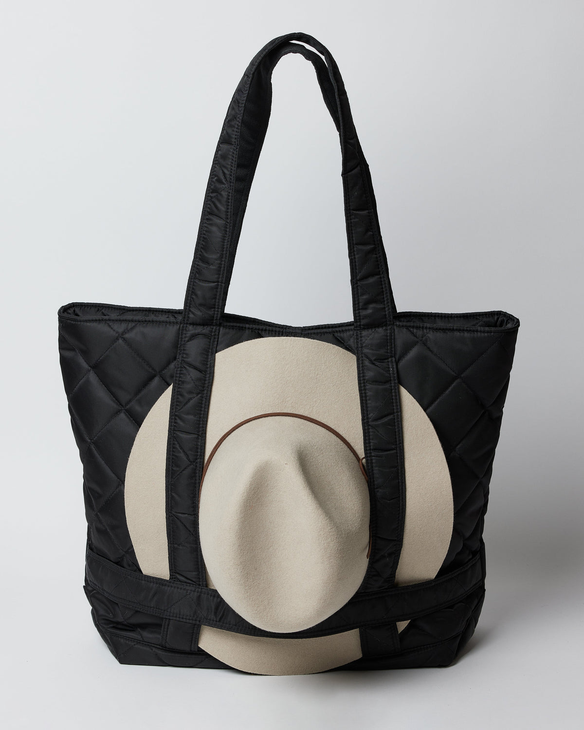 Hat attached to black quilted nylon bag with straps to hold a hat