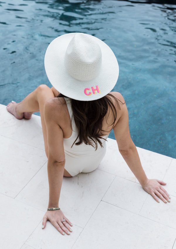 Model wearing embroidered sunhat by the pool