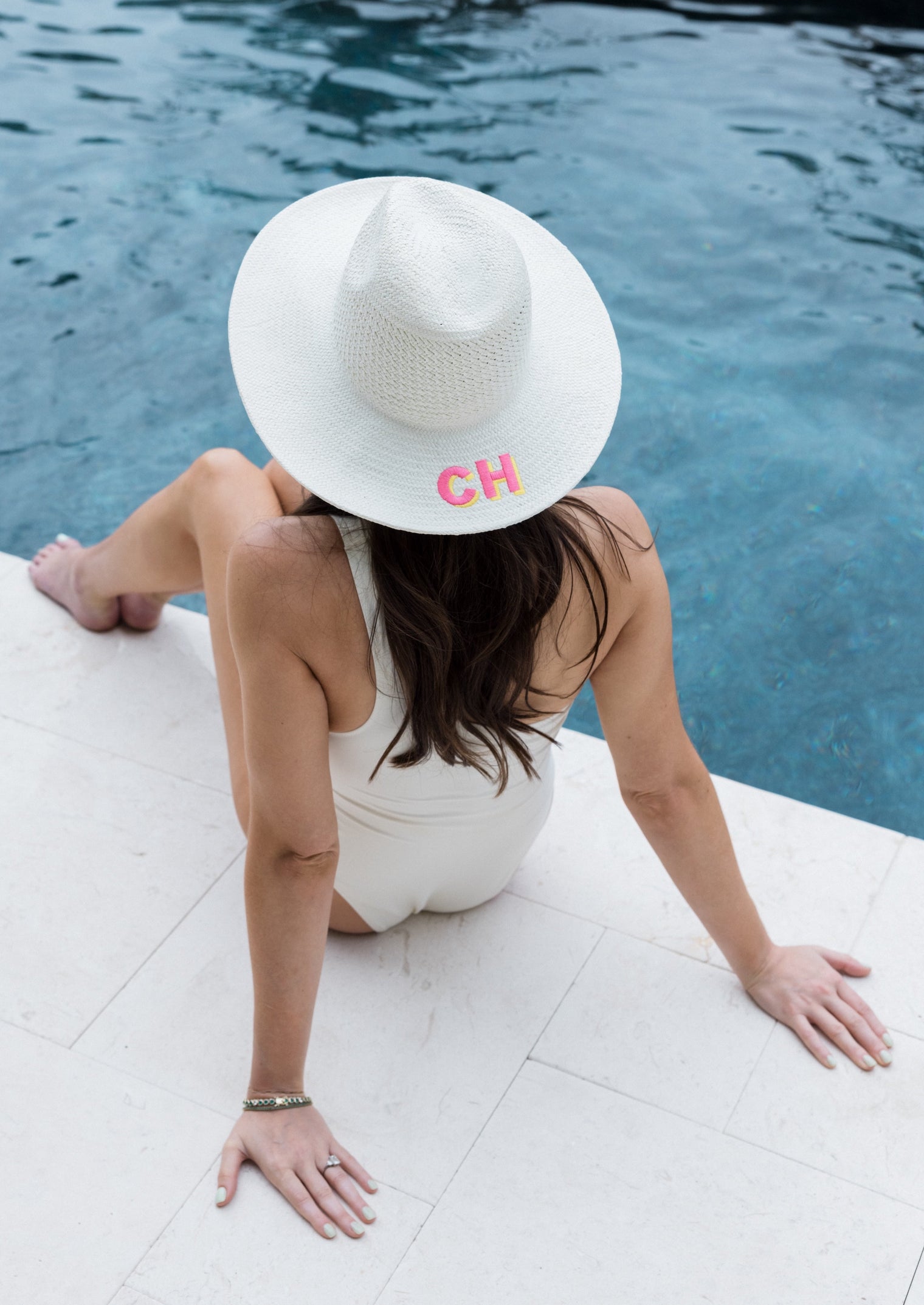 Model wearing bleach colored vented and perforated sun hat with embroidered letters